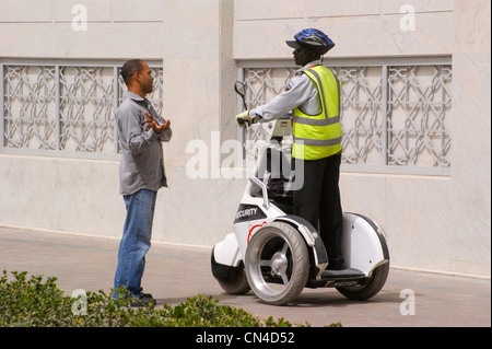 Un homme parlant à un garde de sécurité sur un tricycle Segway, Dubaï, Émirats Arabes Unis Banque D'Images