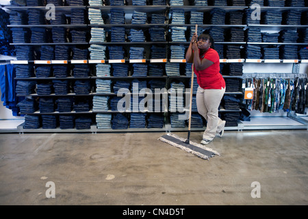 Young woman leaning on balai en magasin de vêtements Banque D'Images