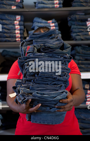 Young woman carrying pile de vêtements en jeans store Banque D'Images