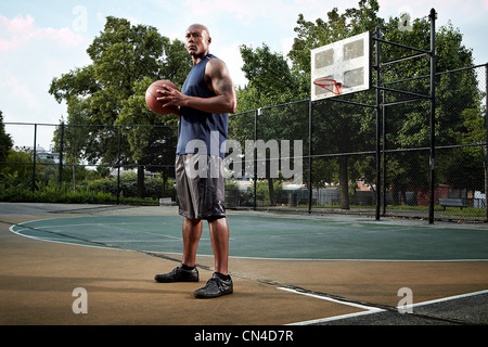 Jeune homme tenant en cour de basket-ball Banque D'Images