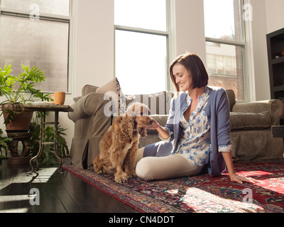 Femme de caresser le chien dans la salle de séjour Banque D'Images