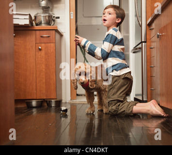 Boy holding tête de chien dans la cuisine Banque D'Images