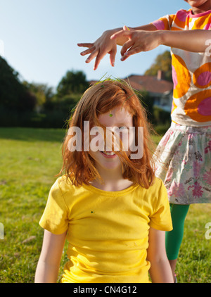 Girl putting l'herbe sur la tête d'amis, portrait Banque D'Images