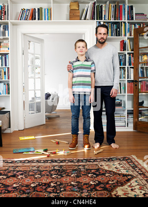 Père et fils se tenant ensemble dans la salle de séjour, portrait Banque D'Images