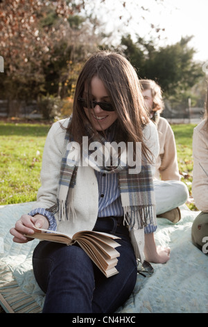 Girl reading book in park Banque D'Images