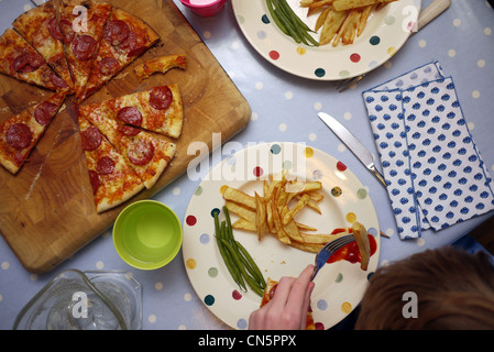 Les enfants de manger un plateau de pizza et frites Banque D'Images