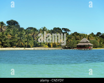 Plage tropicale avec des cocotiers et un restaurant au toit de chaume au-dessus de l'eau, de l'Amérique centrale, Bocas del Toro, PANAMA Banque D'Images