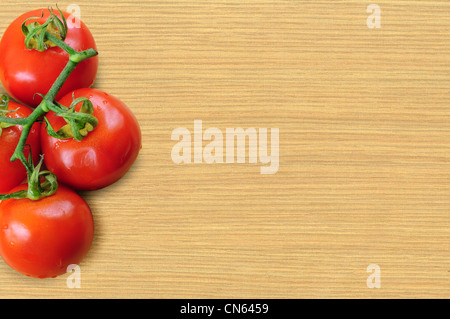 Branche de tomates fraîches sur planche de bois Banque D'Images