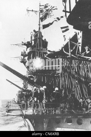 Un équipage de canon a son arme à bord du porte-avions de la Marine impériale japonaise Akagi. Il s'agit d'une position de canon antiaérien double de 120 mm de calibre 45 montée du côté port du porte-avions. Notez que la position est trop basse pour lui permettre de tirer sur la plate-forme de vol. La photo a été prise en novembre ou décembre 1941 alors que le transporteur se dirigeait vers Hawaï pour l'attaque sur Pearl Harbor. Banque D'Images