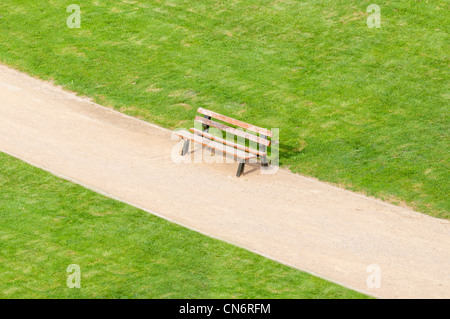 Banc solitaire debout sur park à pied avec pelouse verte par côtés Banque D'Images