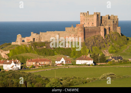 Château de Bamburgh, avec des maisons ci-dessous, vue depuis les collines surplombant le village. , Bamburgh Northumberland. Mai. Banque D'Images