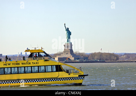 Un New York Water Taxi passe devant la Statue de la liberté dans le port de New York Banque D'Images