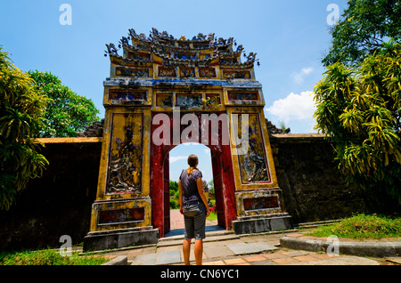 Les jeunes femmes à la recherche dans l'une des nombreuses portes qui entourent la Cité pourpre interdite, Site du patrimoine mondial de l'UNESCO, Hue, Vietnam Banque D'Images