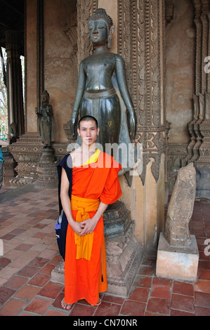 Le moine bouddhiste par Bouddha de bronze statue, Haw Phra Kaew (Temple du Bouddha d'Émeraude), Vientiane, Vientiane, Laos Préfecture Banque D'Images