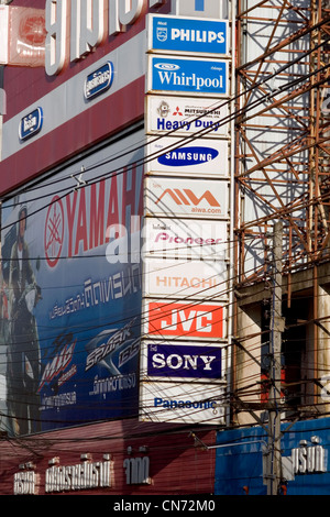 De nombreux signes publicité diverses marques font partie du paysage urbain au-dessus d'une rue de ville de Chiang Rai, Thaïlande. Banque D'Images