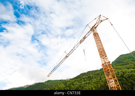 Grue de construction sur place dans des montagnes des Alpes. Blue cloudy sky en arrière-plan et Green Mountain. Banque D'Images