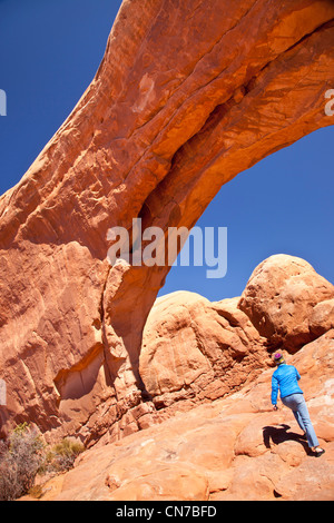 Randonneur solitaire marche au-dessous de la fenêtre du Nord Arch dans Arches National Park, Utah USA Banque D'Images