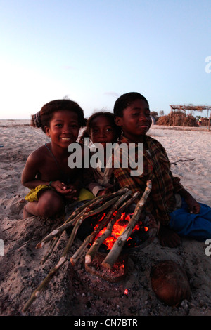 Un groupe d'enfants malgaches de l'ethnie Vezo par un incendie dans un typique village de pêcheurs Vezo à distance et Banque D'Images