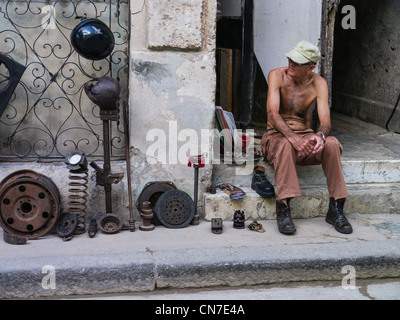 Un homme est assis cubain sur le devant de sa maison se vendre auto parts à La Havane, Cuba. Banque D'Images