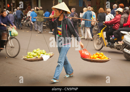 Femme marchant sur une route transportant des fruits dans la vieille ville, Hanoi, Vietnam Banque D'Images