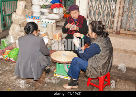 Trois femmes marchands de cartes à jouer sur un trottoir dans la vieille ville, Hanoi, Vietnam Banque D'Images