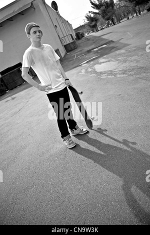 Un jeune adolescent patineur posant dans une zone urbaine avec son conseil. Banque D'Images