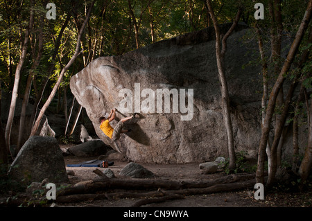 Rock climber scaling boulder face Banque D'Images