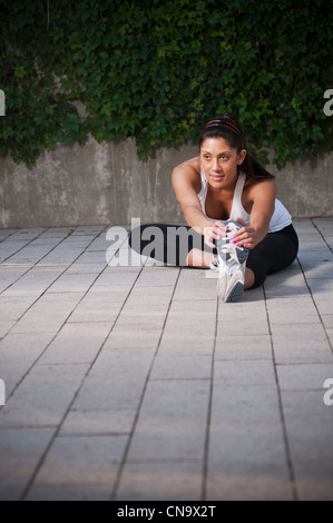 Runner stretching on sidewalk Banque D'Images