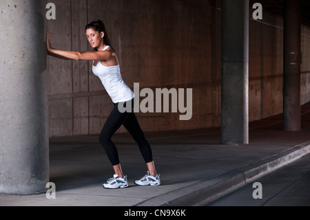 Runner stretching on sidewalk Banque D'Images