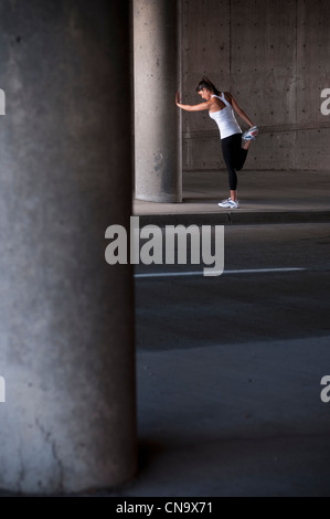 Runner stretching on sidewalk Banque D'Images