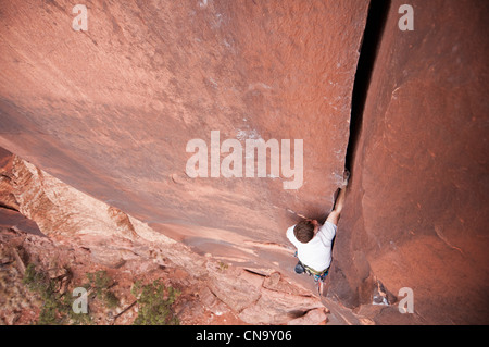 Rock climber scaling boulder crack Banque D'Images