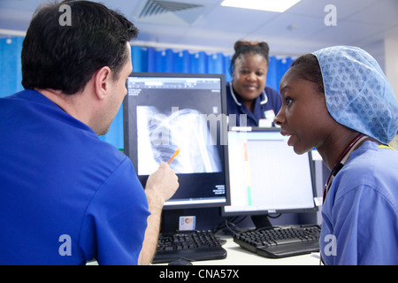Une jeune femme noire médecin parle avec un collègue à propos d'un x-ray aux urgences UK Banque D'Images