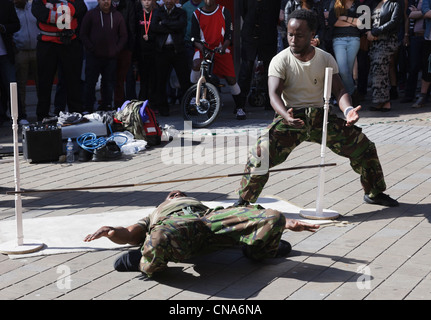 Des artistes de rue danse limbo sous un poteau avec un public d'observer les gens à Leeds Yorkshire Angleterre UK Banque D'Images