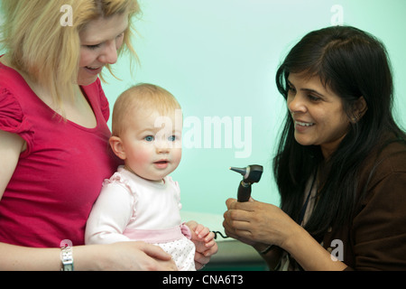 Une femme médecin examine une jeune fille avec un otoscope UK Banque D'Images