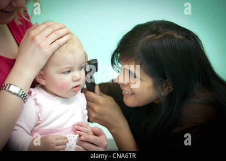 Une femme médecin examine une jeune fille avec un otoscope UK Banque D'Images