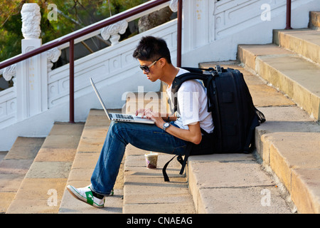 Jeune homme travaillant sur ordinateur portable Apple MacBook assis sur les marches de Wenwu Temple, Sun Moon Lake, Taiwan. JMH5880 Banque D'Images