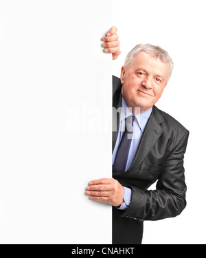 Smiling mature woman holding a white panneau et gesticulant isolé sur fond blanc Banque D'Images