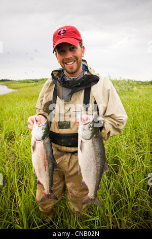 Pêcheur de mouche contient jusqu'deux saumons rouges sur la Mulchatna River dans la région de la baie de Bristol, sud-ouest de l'Alaska, l'été Banque D'Images