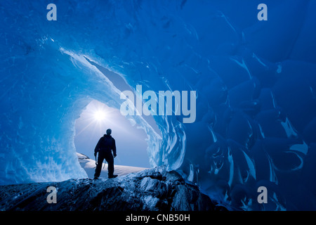 COMPOSITE : Vue de l'intérieur d'une grotte de glace d'un iceberg frozen dans Mendenhall Lake comme un grimpeur sur glace se tient à l'entrée, de l'Alaska Banque D'Images