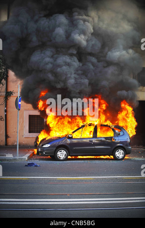 Des émeutes dans la rue, location hors de contrôle. Le véhicule est enveloppé dans des incendies et la fumée de la tenture qui rend impossible d'éteindre les flammes. Banque D'Images
