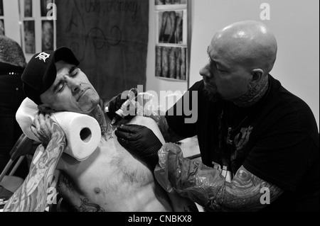 Un homme grimace de douleur tout en étant tatoué à la Edinburgh Tattoo Convention 2012 à Édimbourg, en Écosse. Banque D'Images