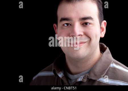 Un sourire heureux homme dans la fin des années 20 sur une isolé sur fond noir foncé. Technique d'éclairage Low key. Banque D'Images