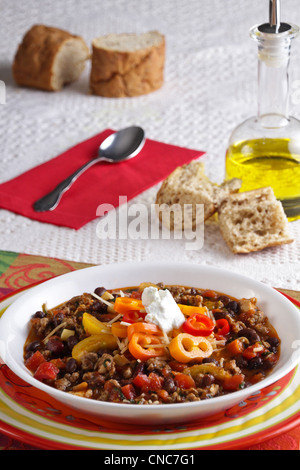 Un bol de soupe minestrone de légumes avec du pain de blé entier et de l'huile d'olive et une cuillère sur la table comme un lieu. Banque D'Images