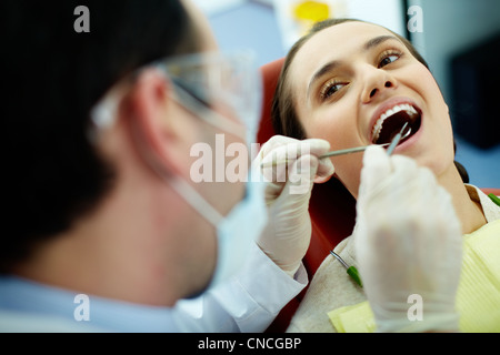 Smiling woman sitting in dentist's chair alors que médecin examinant les dents Banque D'Images