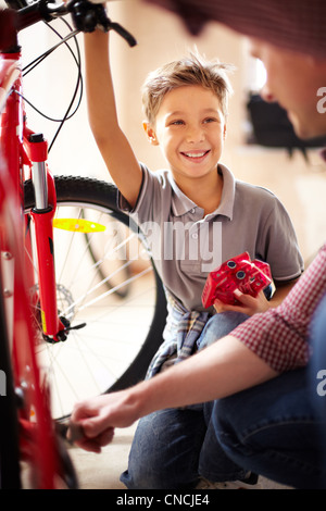 Portrait of cute boy à son père à la réparation de vélo dans garage Banque D'Images