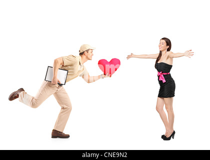 Livreur pressé la prestation en forme de coeur rouge oreiller et excited woman isolé sur fond blanc Banque D'Images