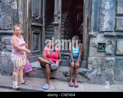 Trois femmes cubaines s'asseoir à l'avant de l'abaisser leur maison dans la section de la Habana Vieja, Cuba La Havane. Banque D'Images