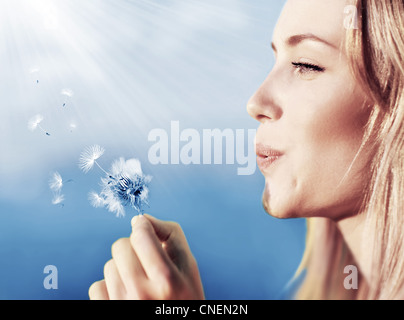 Happy woman blowing dandelion sur fond de ciel, s'amuser et jouer en plein air, teen girl enjoying nature Banque D'Images