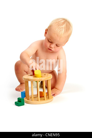 Un mignon bébé garçon enfant en concentrant jouant avec un trieur de forme toy isolé sur fond blanc Banque D'Images