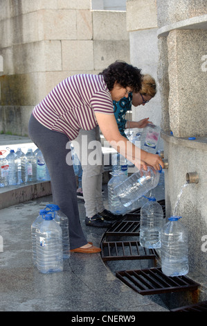 Les gens d'eau de remplissage de bidons à une fontaine publique de Luso, Portugal Banque D'Images